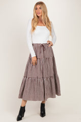 woman wearing a white long sleeve top and a brown and white checkered maxi skirt with a tie waist