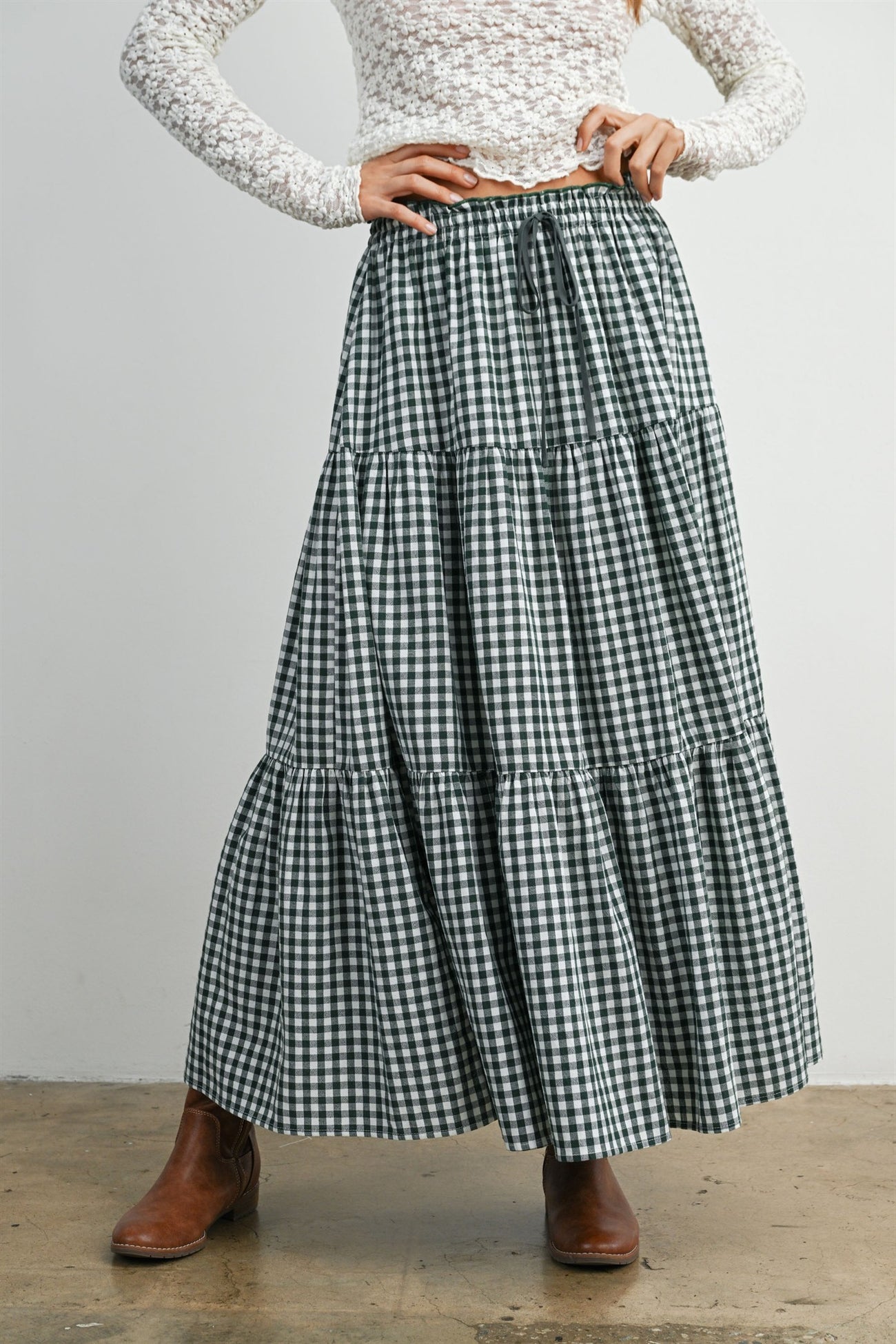 woman wearing a green and white gingham tiered maxi skirt with a drawstring waist and brown ankle boots