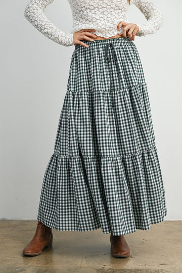 woman wearing a green and white gingham tiered maxi skirt with a drawstring waist and brown ankle boots