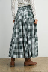 woman wearing a green and white gingham maxi skirt with tiered ruffles, styled with brown ankle boots