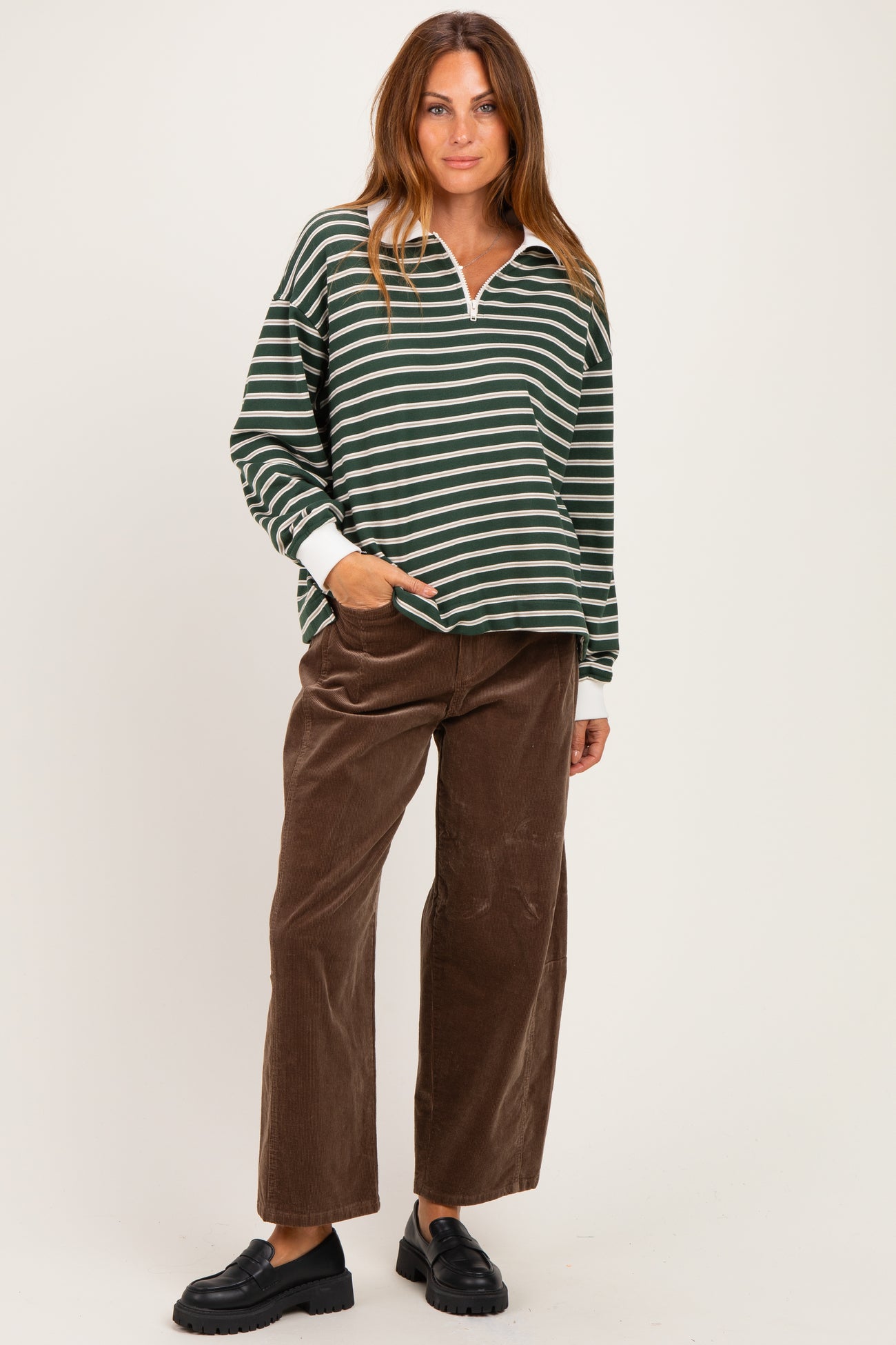 woman wearing a green and white striped long sleeve pullover with a collar and brown wide-leg corduroy pants
