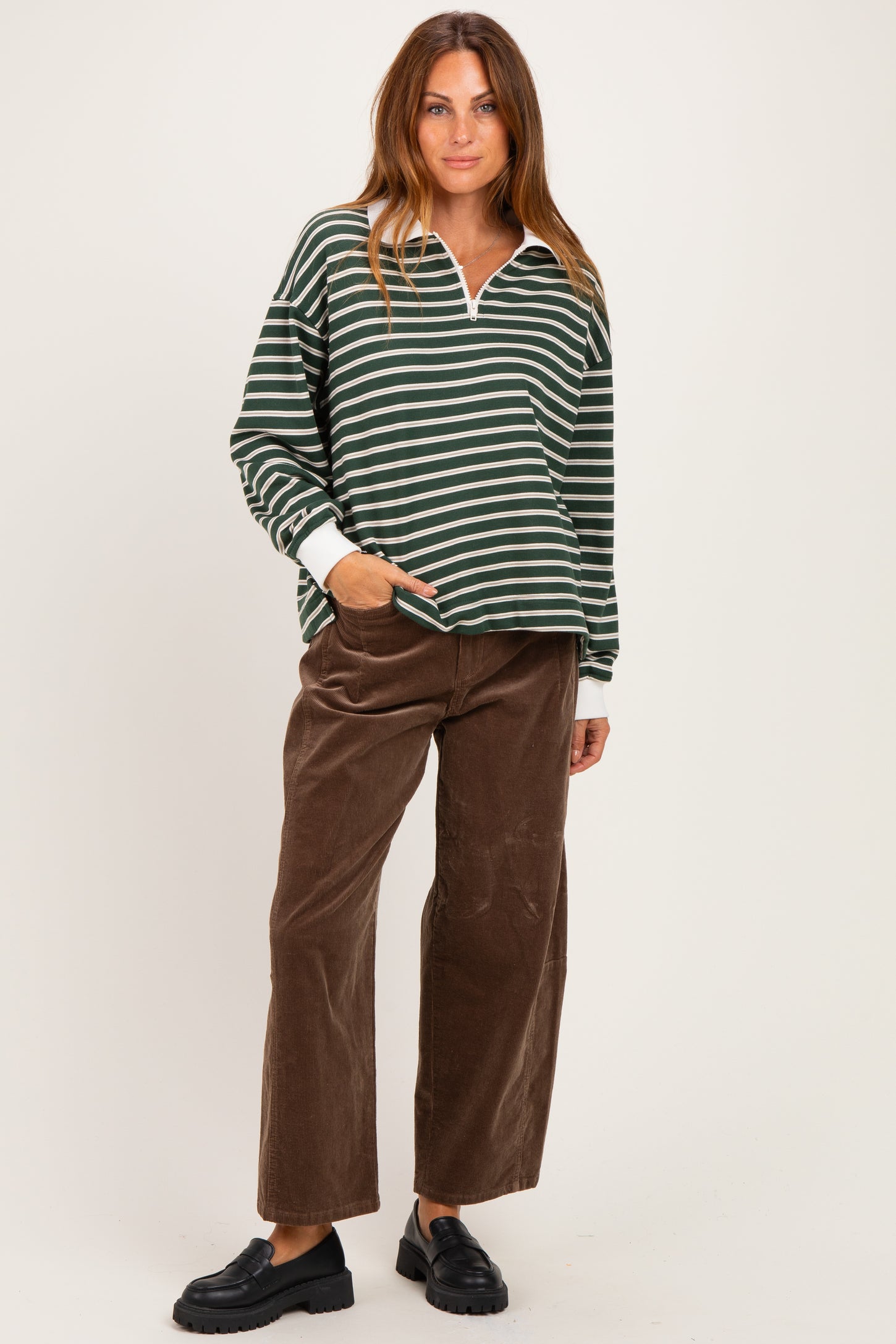 woman wearing a green and white striped long sleeve pullover with a collar and brown wide-leg corduroy pants