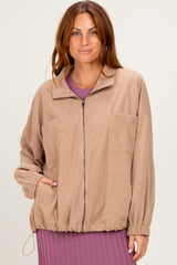 woman wearing a light brown corduroy zip-up jacket with two front pockets and elasticized hem over a purple dress