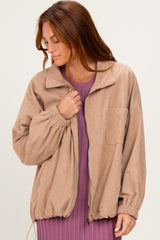 woman wearing a tan corduroy jacket with a zip front and oversized fit over a purple ribbed dress