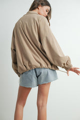 woman wearing a beige corduroy jacket with a cinched waist and paired with light blue denim shorts