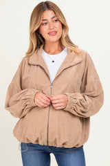 woman wearing a tan corduroy maternity jacket with a zip front and puffed sleeves, no visible baby bump