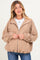 woman wearing a tan corduroy maternity jacket with a zip front and puffed sleeves, no visible baby bump
