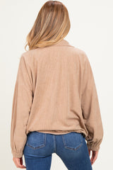 woman wearing a light brown maternity corduroy top with back pleats and relaxed fit, paired with blue jeans