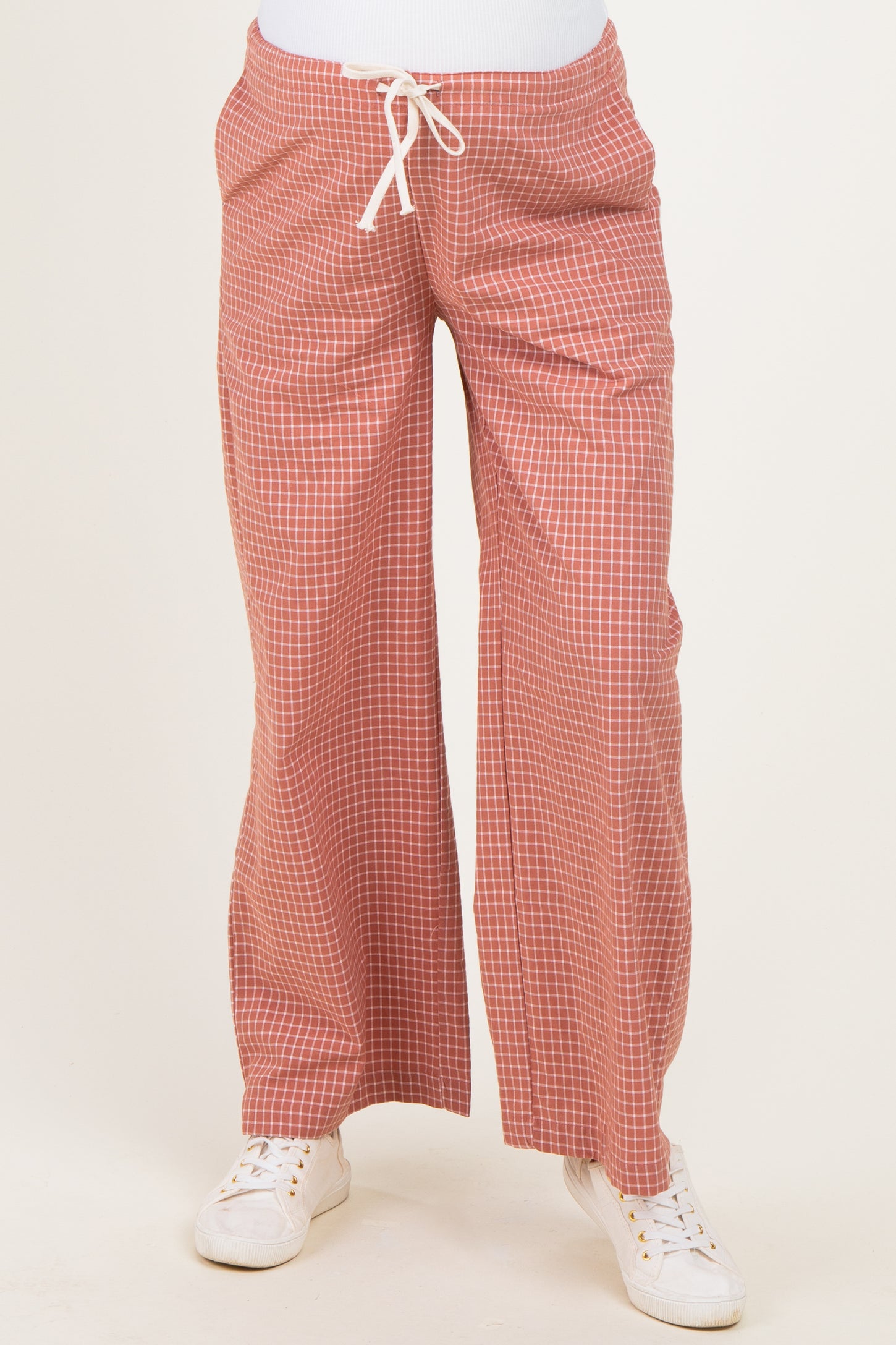 woman wearing red checked maternity pants with a loose fit and drawstring waist, styled with white sneakers