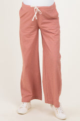 woman wearing red checked maternity pants with a loose fit and drawstring waist, styled with white sneakers