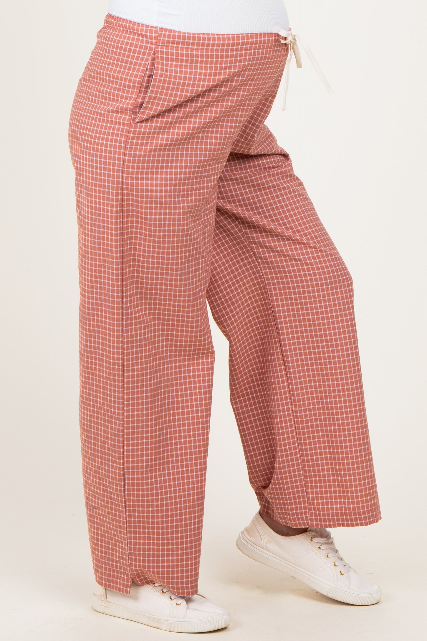 woman wearing coral checked maternity pants with a drawstring waistband and a visible baby bump