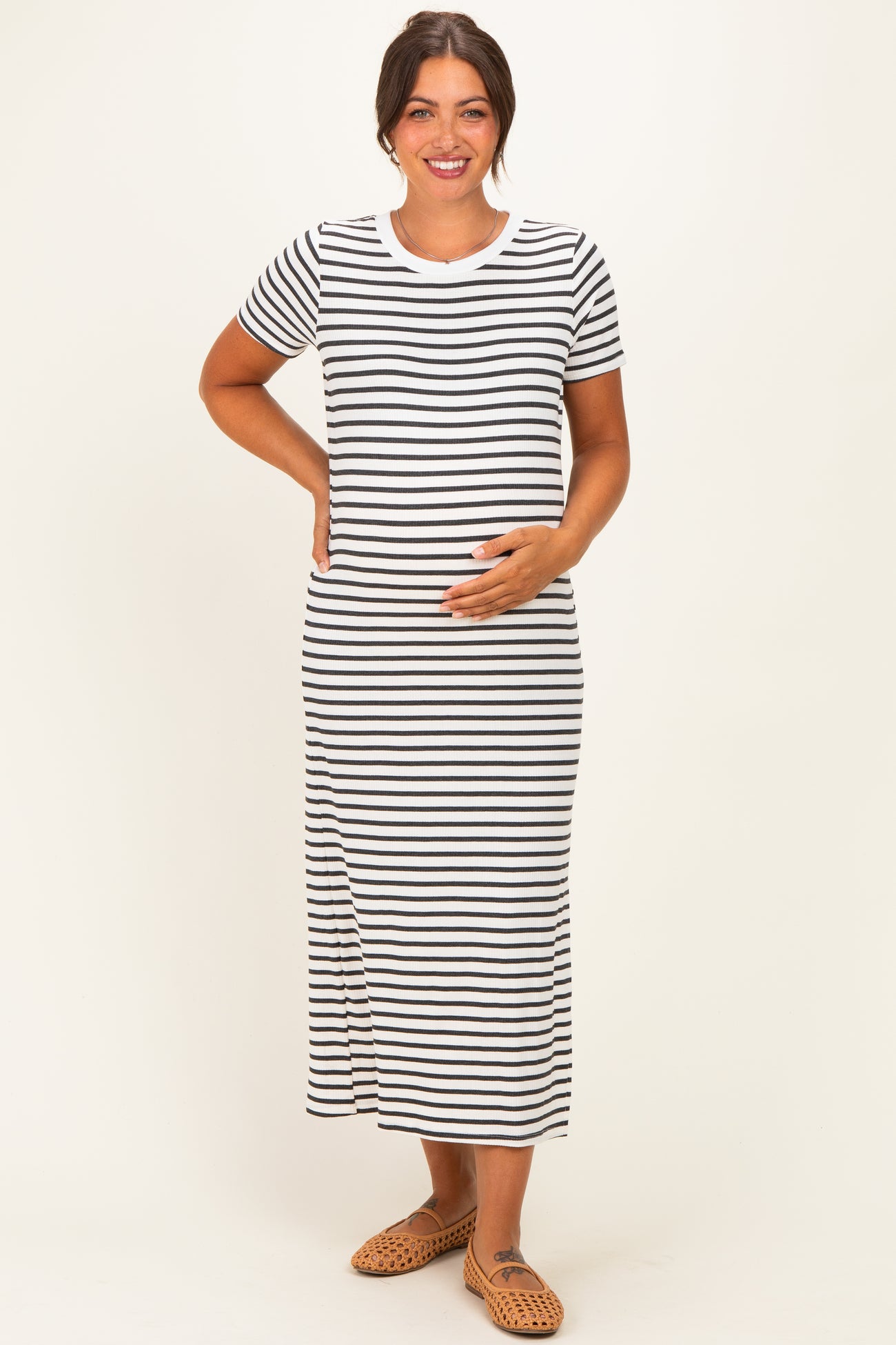 woman wearing a black and white striped maternity maxi dress and holding her baby bump