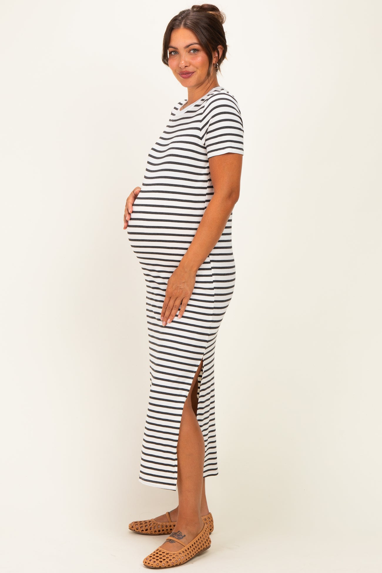 woman wearing a black and white striped maternity dress with side slits and a visible baby bump