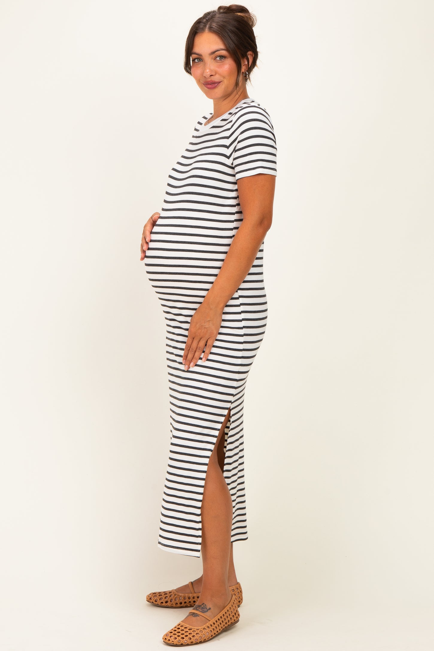 woman wearing a black and white striped maternity dress with side slits and a visible baby bump