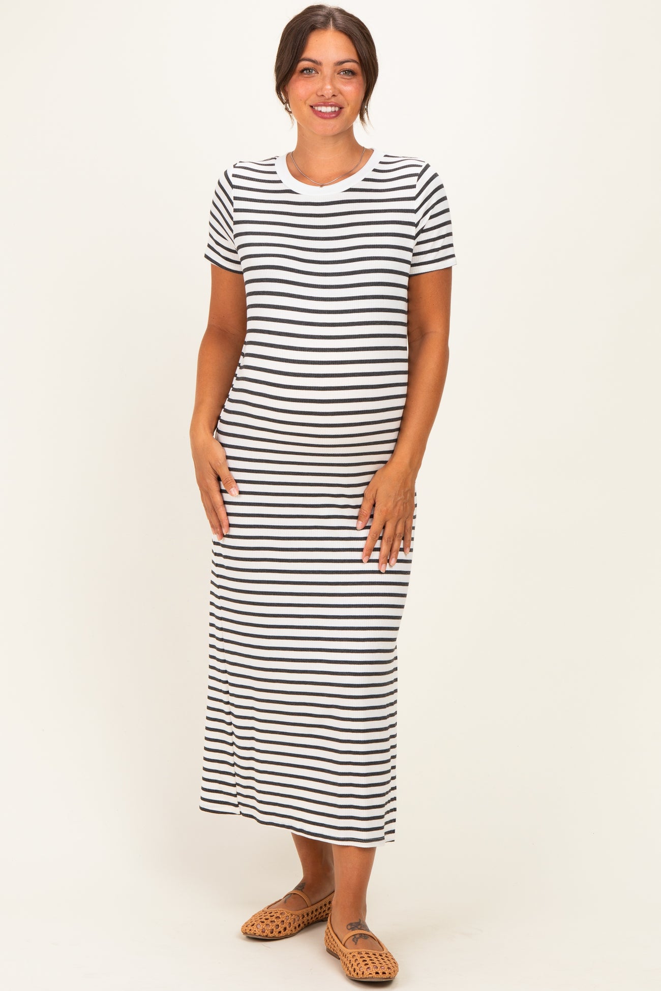 woman wearing a black and white striped maternity maxi dress with a fitted silhouette and short sleeves, showing her baby bump