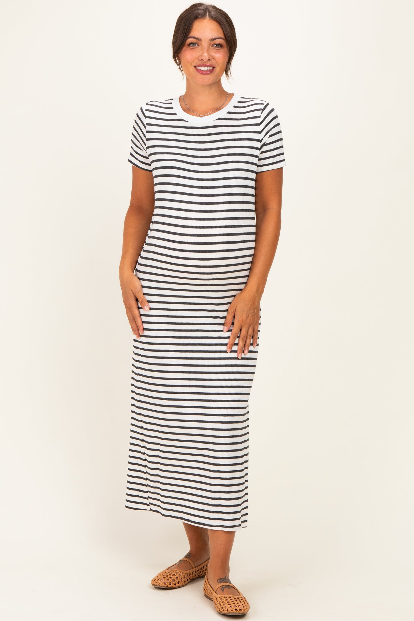woman wearing a black and white striped maternity maxi dress with a fitted silhouette and short sleeves, showing her baby bump