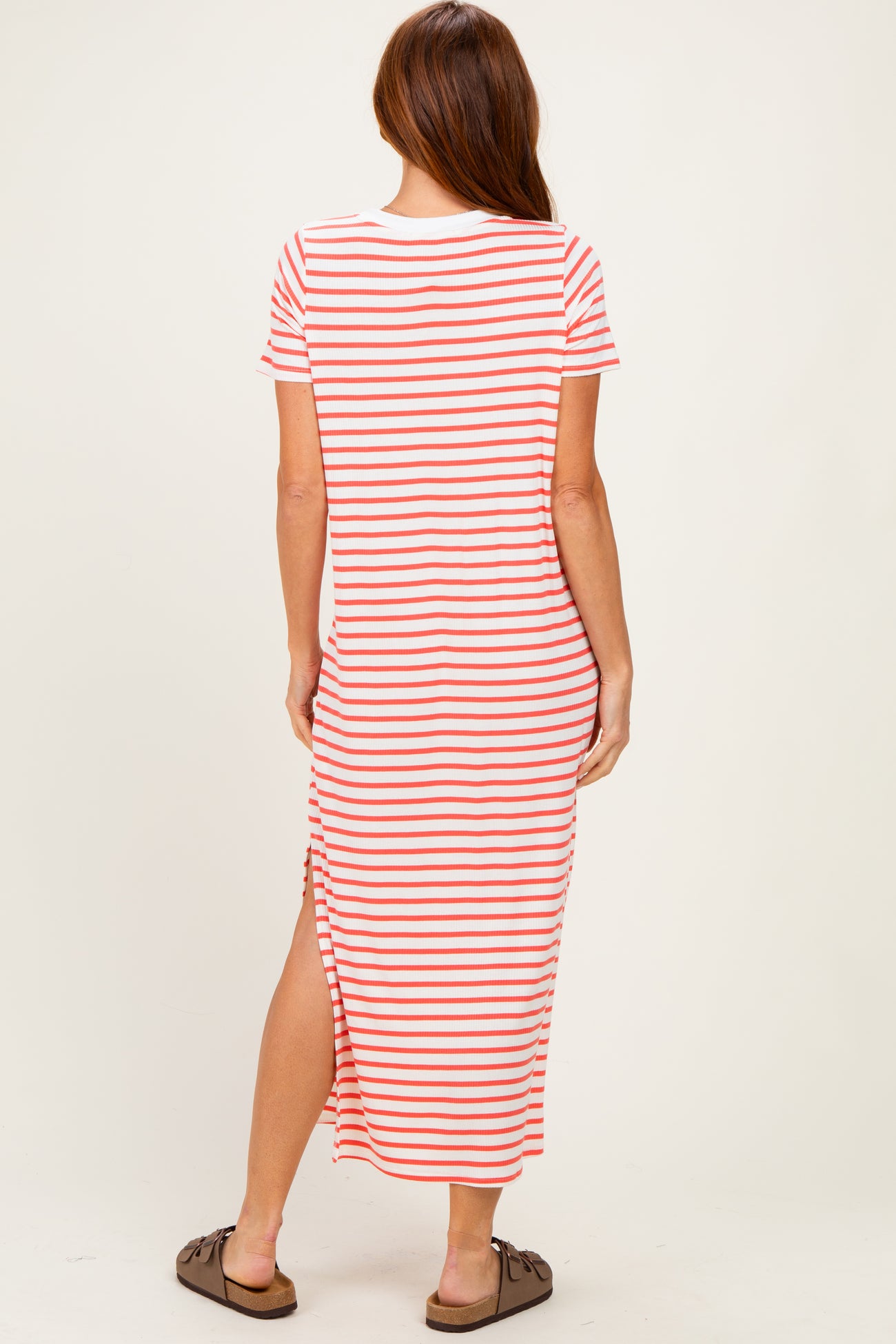 woman wearing a striped maxi dress with short sleeves and side slits, viewed from the back