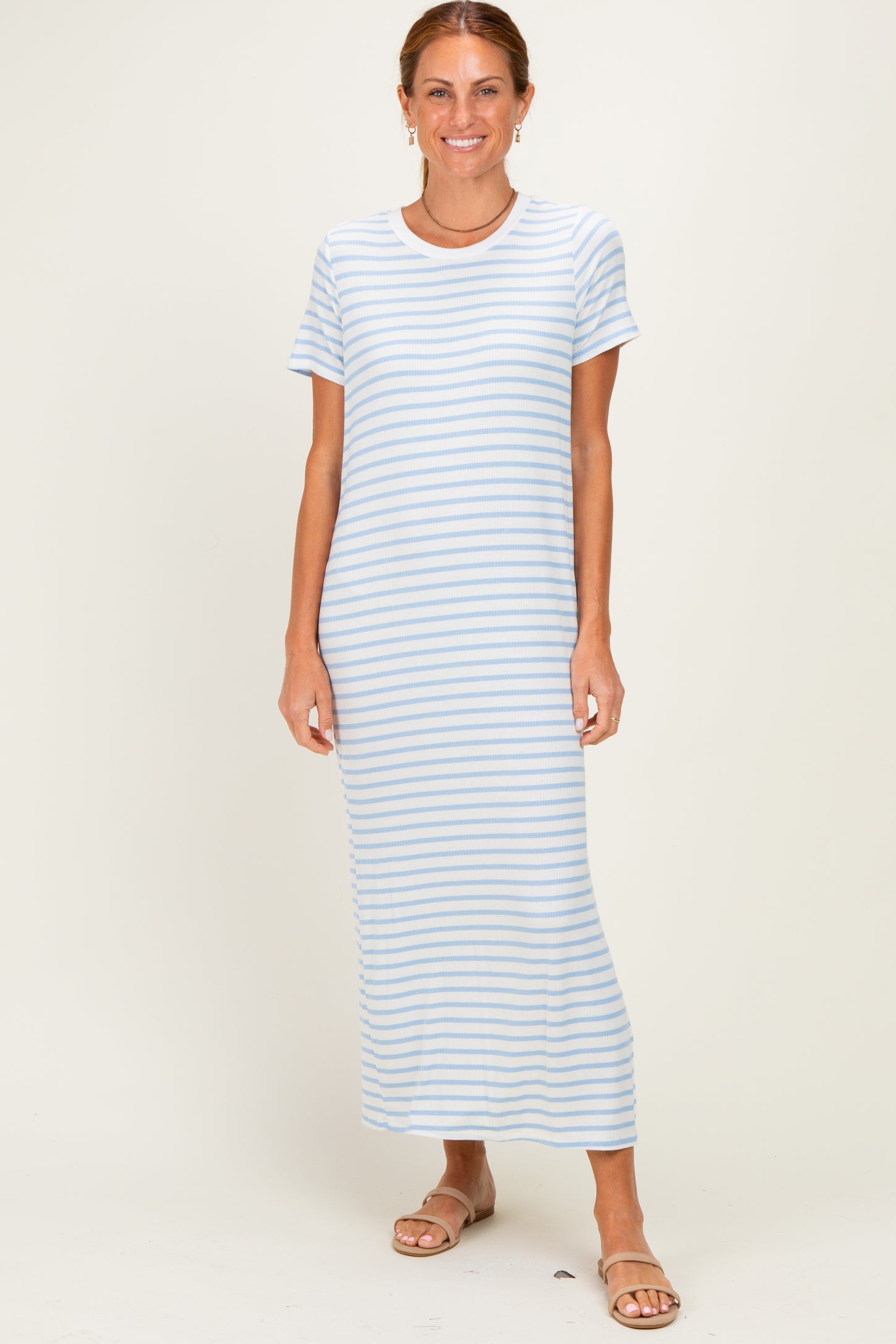woman wearing a light blue striped maxi dress with short sleeves and standing in a neutral background