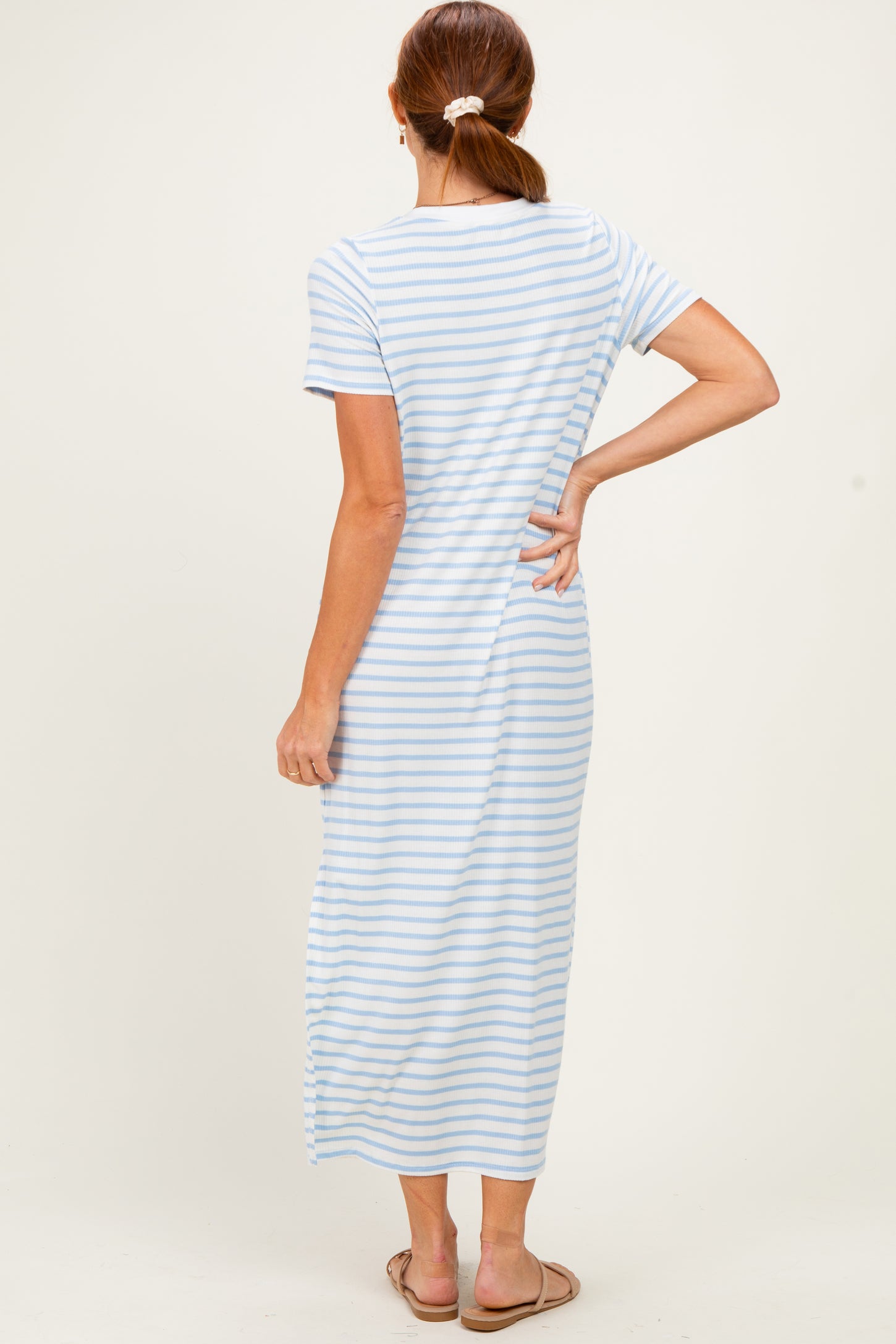 woman wearing a light blue and white striped maxi dress with short sleeves, showing the back view