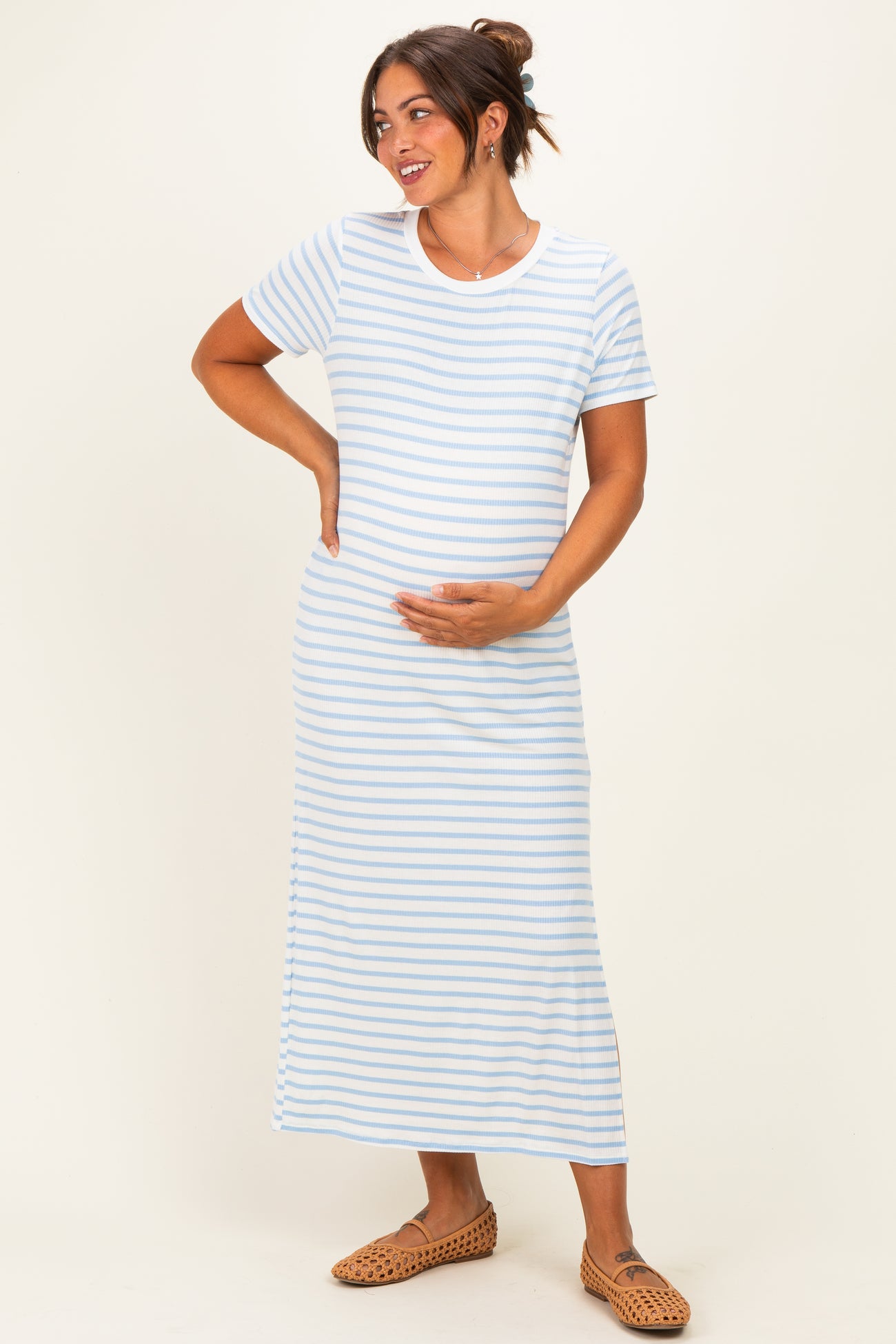 woman wearing a light blue striped maternity maxi dress and holding her baby bump