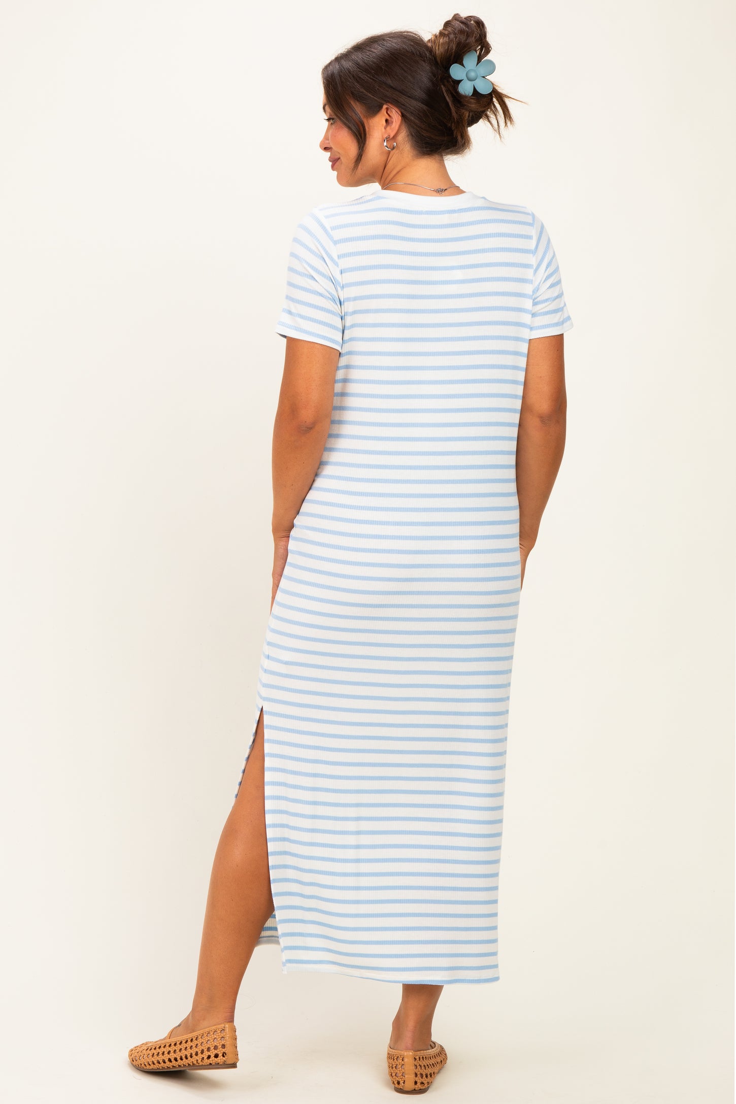 woman wearing a light blue striped maternity maxi dress with short sleeves and a side slit