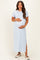 woman wearing a light blue maxi maternity dress with short sleeves and a side slit, holding her baby bump