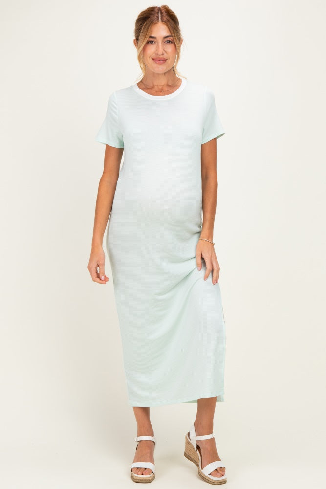 woman wearing a light green short sleeve maternity dress and showing her baby bump