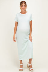 woman wearing a light green short sleeve maternity dress and showing her baby bump