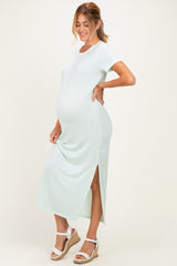 woman wearing a light mint green maternity maxi dress with side slits and a visible baby bump