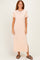 woman wearing a light peach short sleeve maxi dress with a round neckline and side slit, standing and smiling