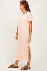 woman wearing a light peach short sleeve maxi dress with side slits and brown slide sandals
