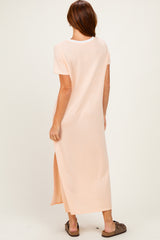 woman wearing a peach short sleeve maxi dress with a side slit, standing with her back to the camera