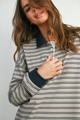 woman wearing a beige and navy striped polo shirt with a button placket and long sleeves