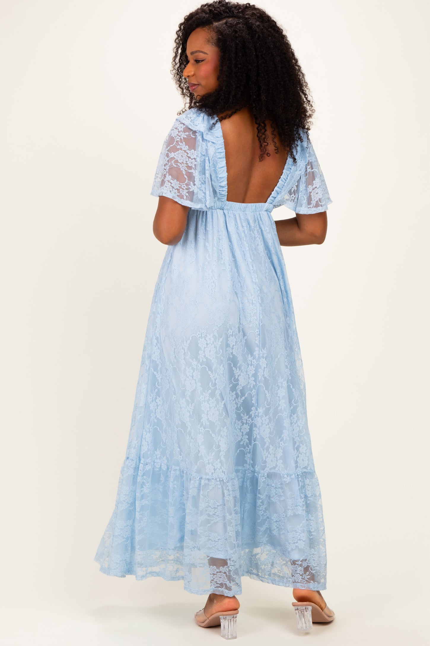woman wearing a light blue lace maxi dress with a backless design and flared sleeves, shown from the back