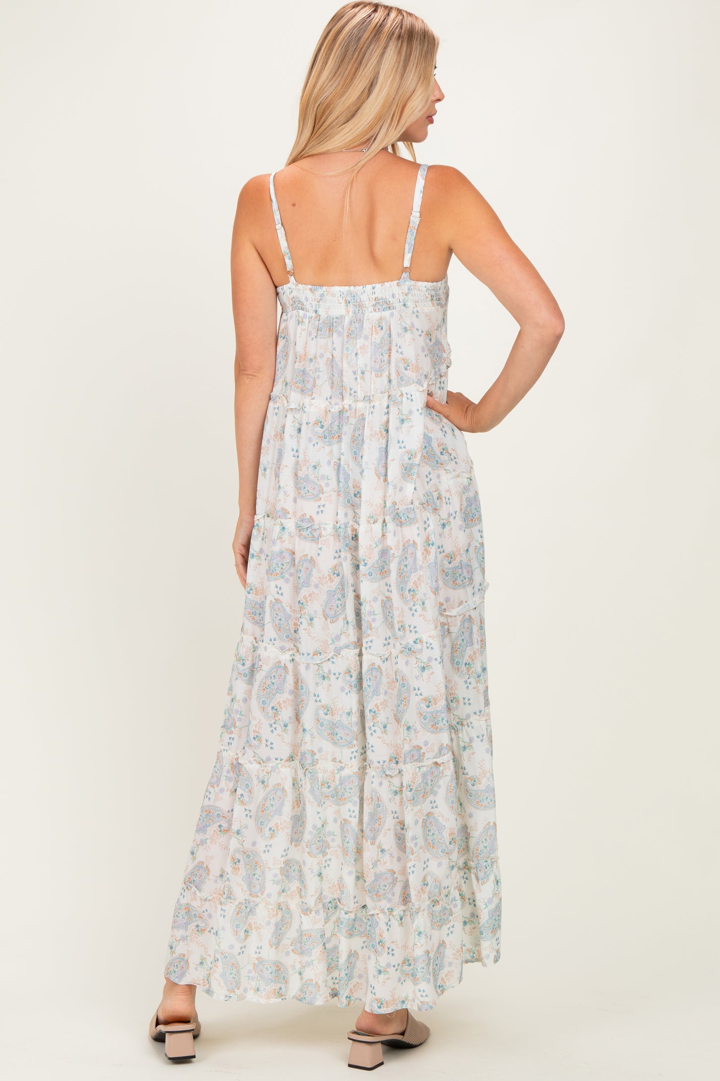 woman wearing a light floral maxi dress with adjustable straps, showing a flowy silhouette from the back