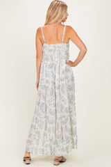 woman wearing a light floral maxi dress with adjustable straps, showing a flowy silhouette from the back