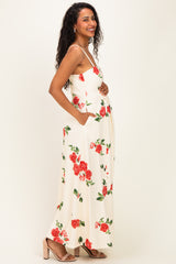 woman wearing a cream floral maternity maxi dress with a baby bump and pockets, smiling and standing sideways