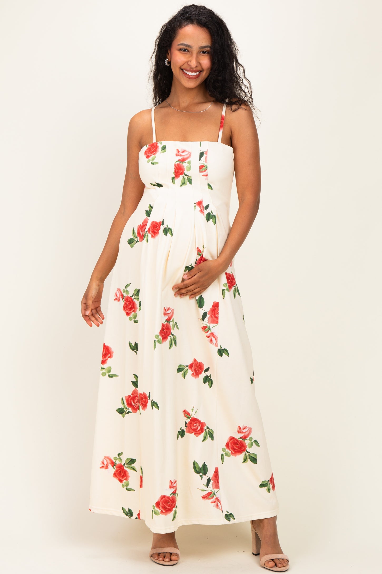 woman wearing a floral maternity maxi dress with spaghetti straps and holding her baby bump