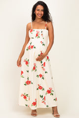 woman wearing a floral maternity maxi dress with spaghetti straps and holding her baby bump
