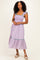 woman wearing a lavender checkered midi dress with ruffle straps and a tiered hem, styled with platform sandals