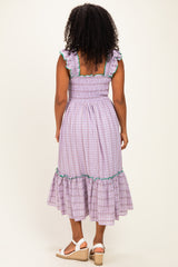 woman wearing a purple checkered dress with ruffled sleeves and a tiered skirt, shown from the back