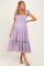 woman wearing a lilac gingham maternity dress with ruffled sleeves and a tiered skirt detail
