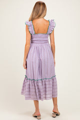 woman wearing a purple and green checkered maternity dress with ruffled sleeves and a tiered skirt, showing her back