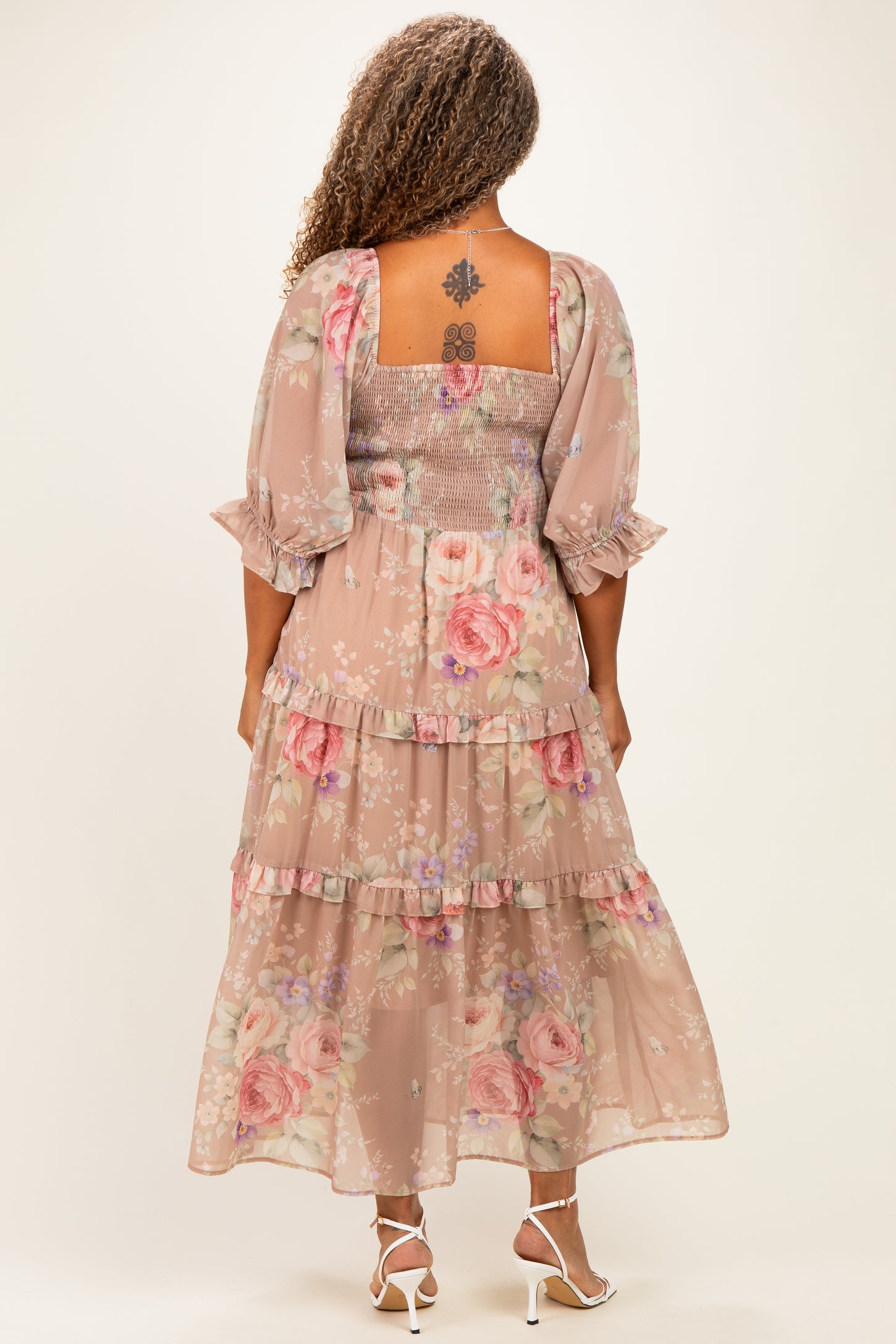woman wearing a floral plus size maxi dress with puff sleeves and a tiered skirt, viewed from the back