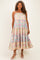 woman wearing a floral midi dress with pink and blue patterns, featuring tiered ruffles and adjustable straps