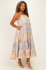 woman wearing a floral plus size maxi dress with pockets and adjustable straps, standing against a light background