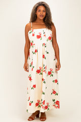 woman wearing a floral print maxi dress with red roses on a cream background, featuring adjustable straps and a flowing silhouette