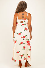 woman wearing a floral maxi dress with a cream background and red roses, showing the back view and strappy design