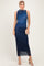 woman wearing a navy blue sleeveless midi dress with ruching and a sheer hem, holding a small clutch purse