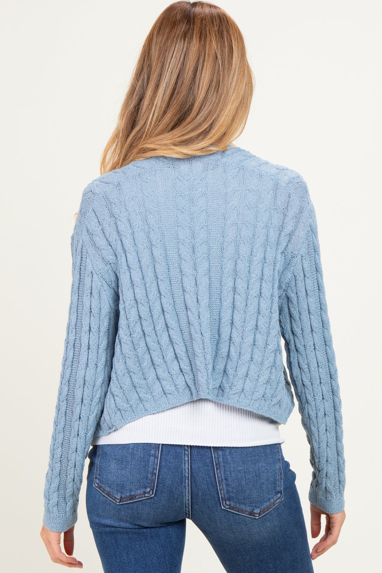 woman wearing a light blue cable knit maternity cardigan with a relaxed fit and ribbed detail at the hem